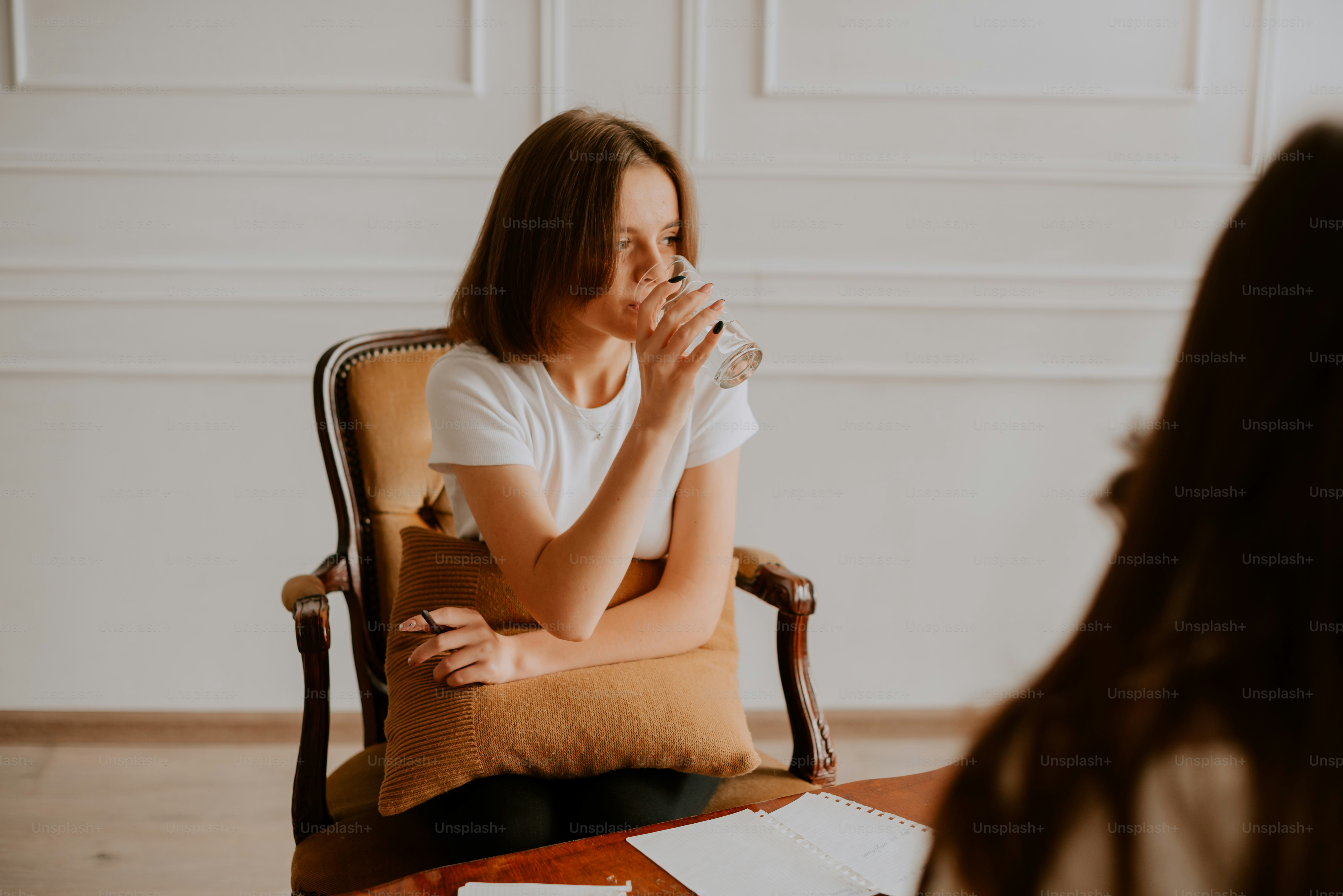 une femme assise sur une chaise buvant dans un verre