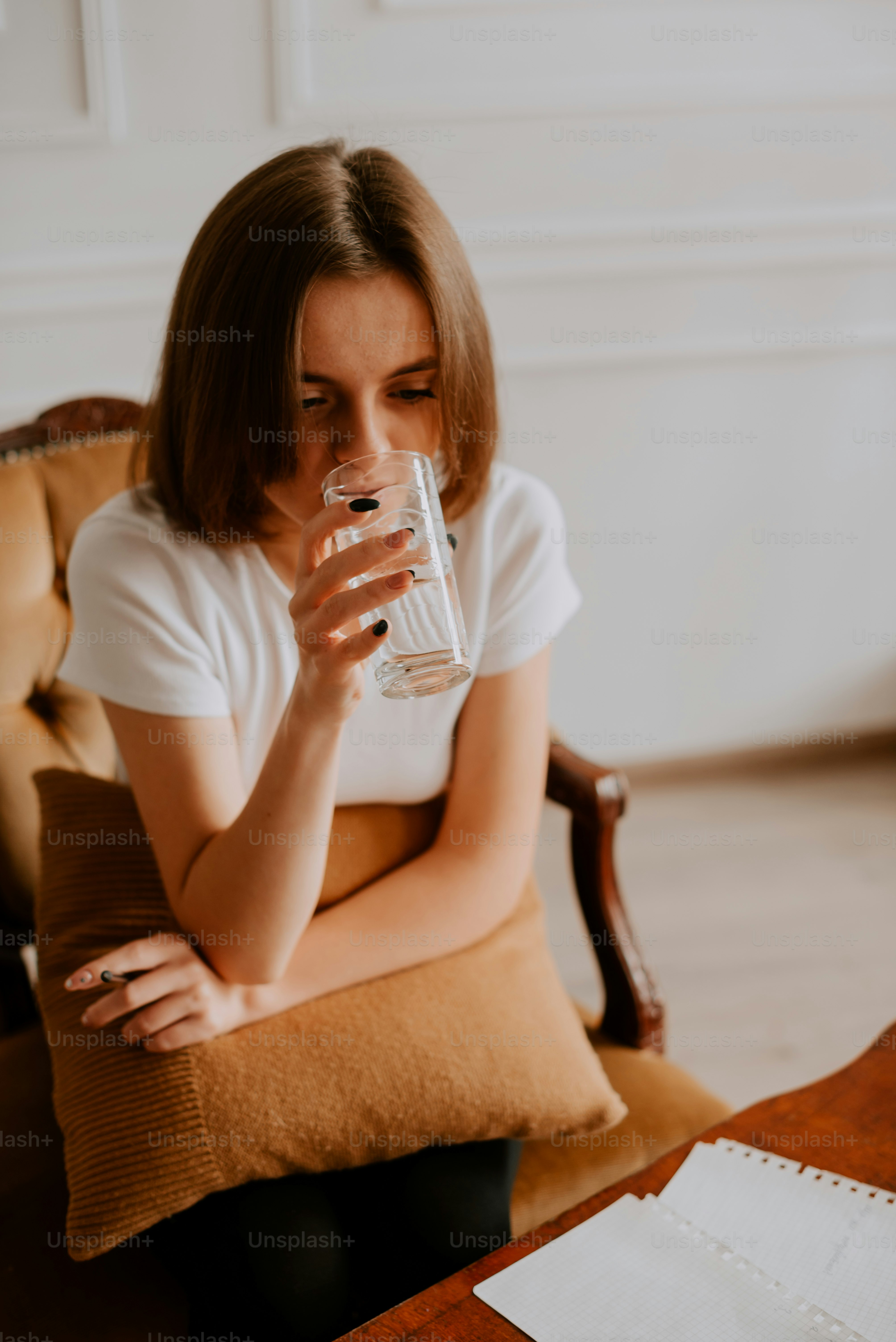 Eine Frau, die auf einem Stuhl sitzt und aus einem Glas trinkt