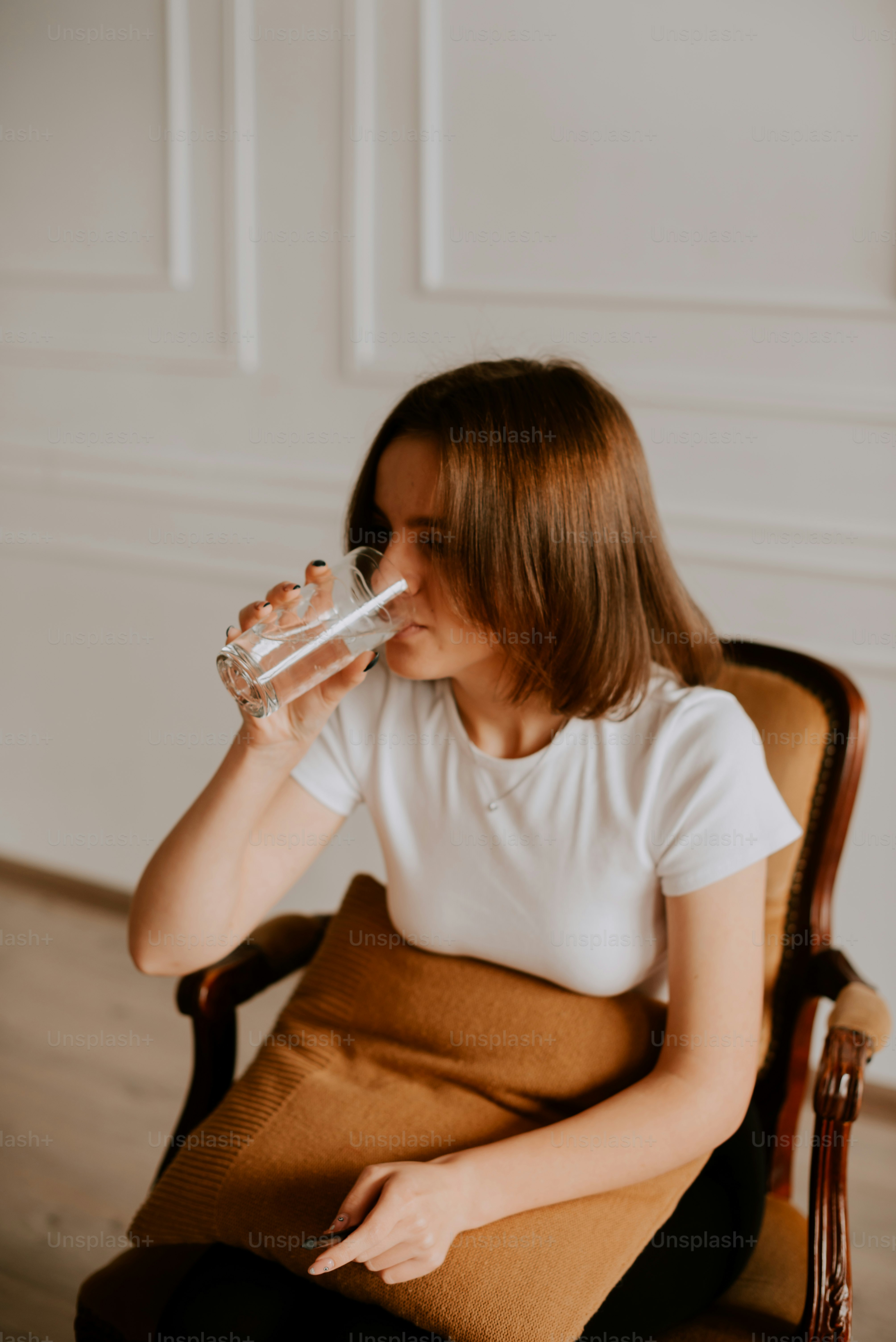 Una mujer sentada en una silla bebiendo un vaso de agua
