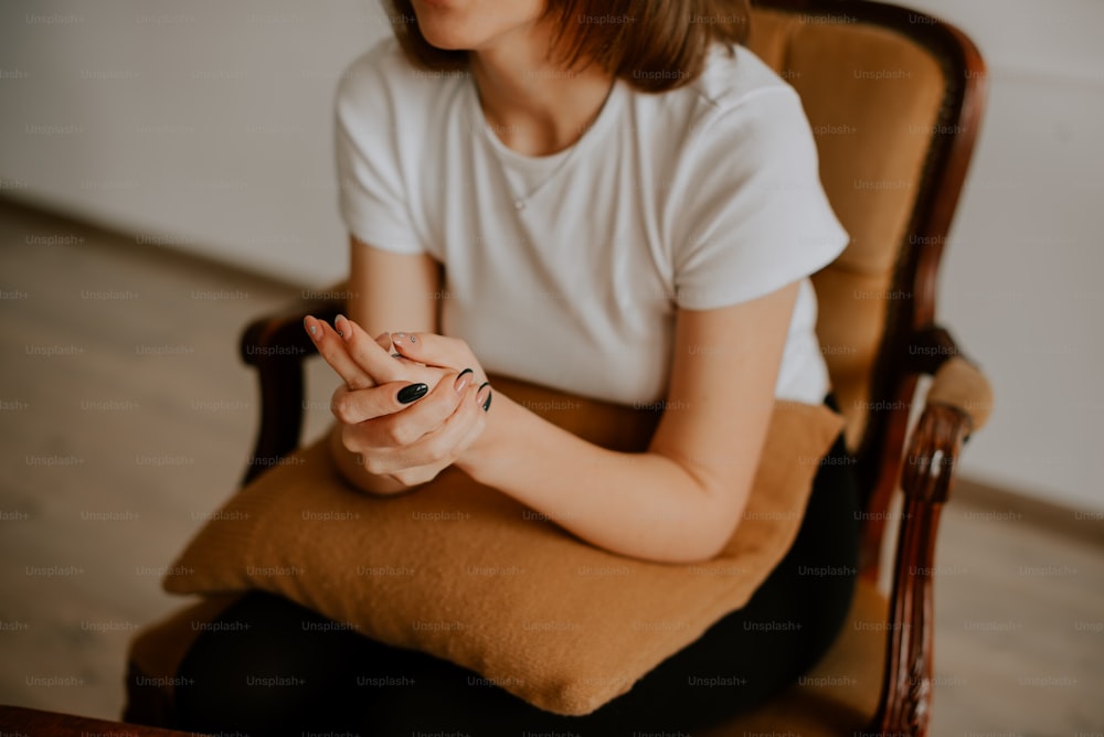 a woman sitting in a chair holding her hands together