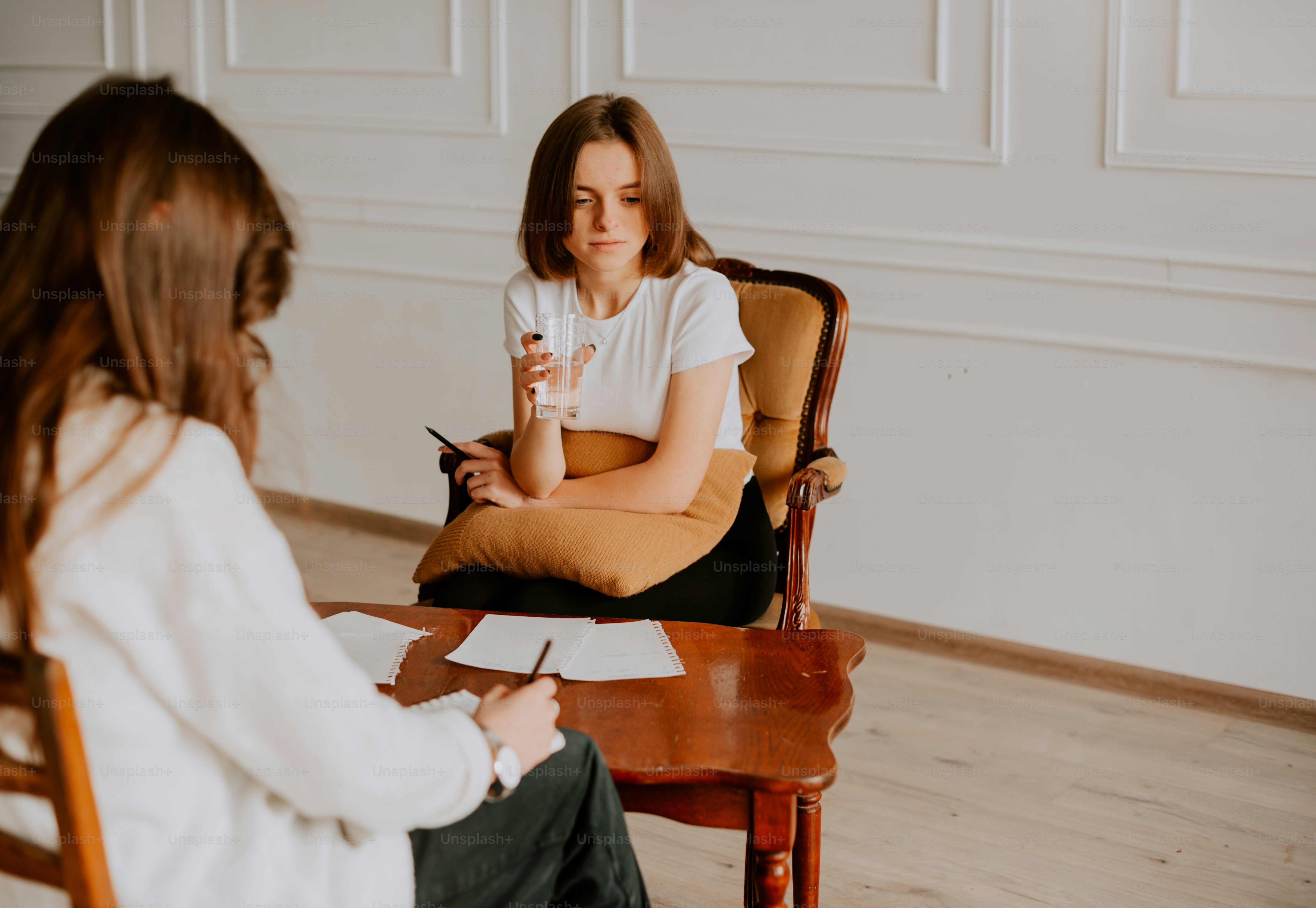 Eine Frau, die auf einem Stuhl sitzt und mit einer anderen Frau spricht