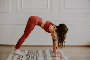 a woman doing a yoga pose on a rug