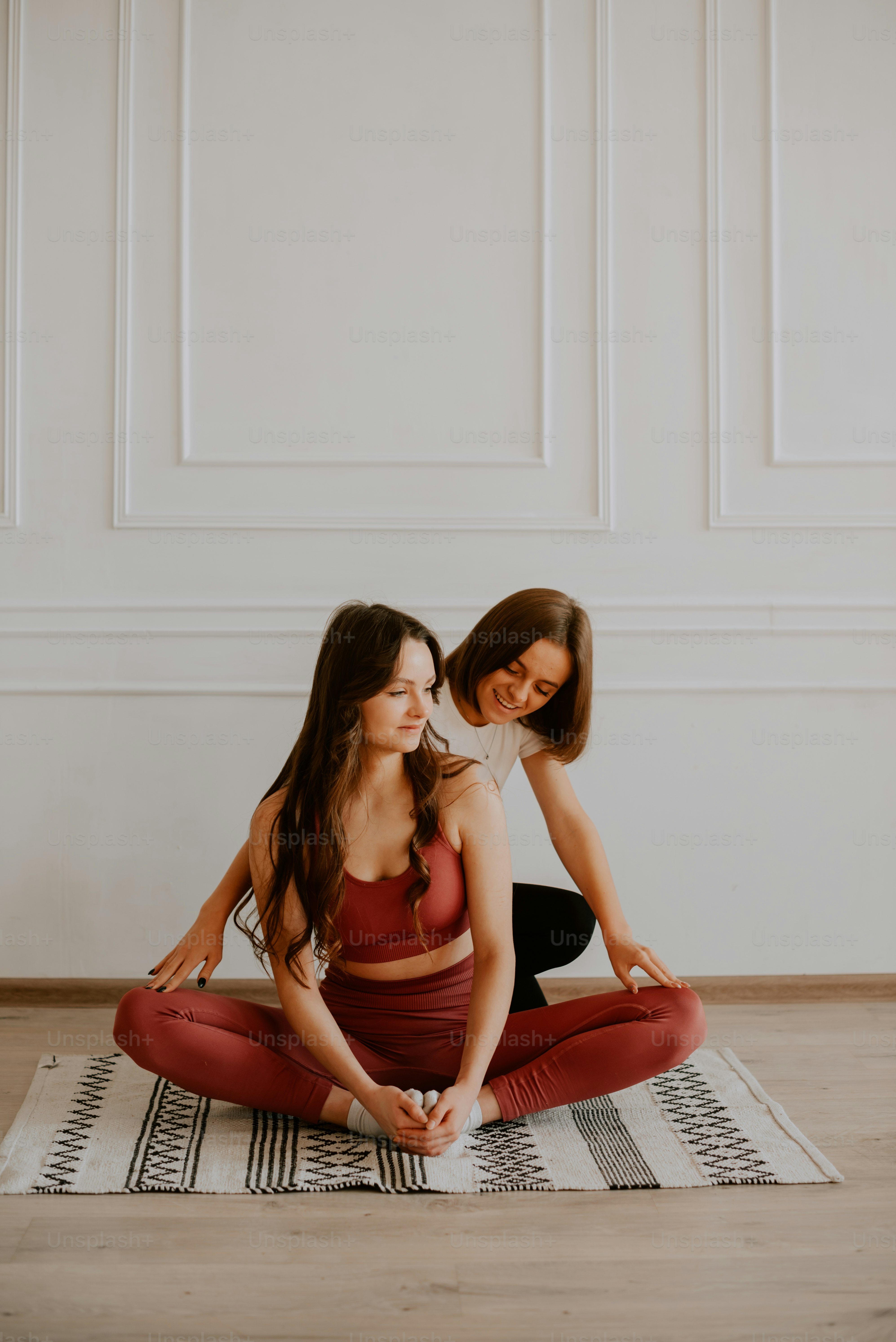two women sitting on a rug in a room