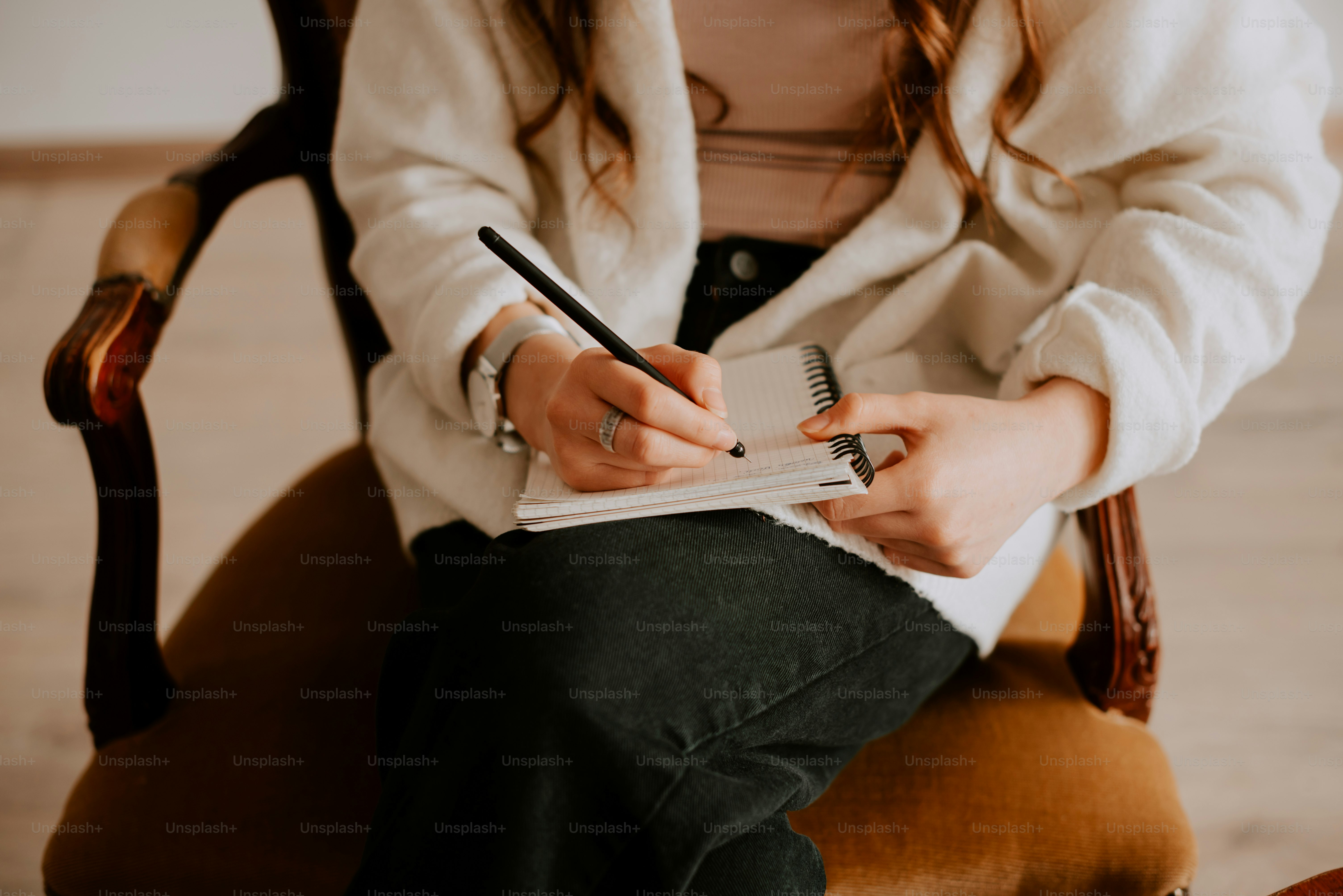 a woman sitting in a chair writing on a notepad