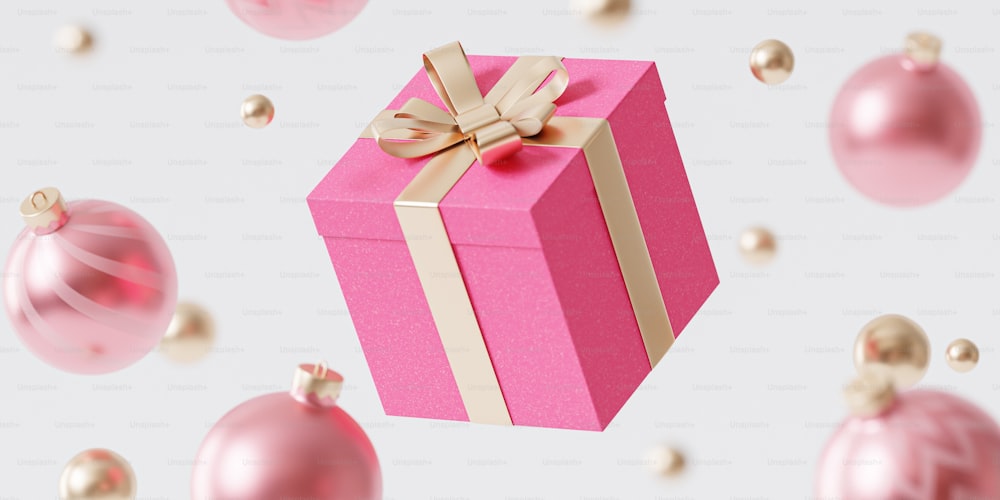 a pink gift box with a gold ribbon and a bow