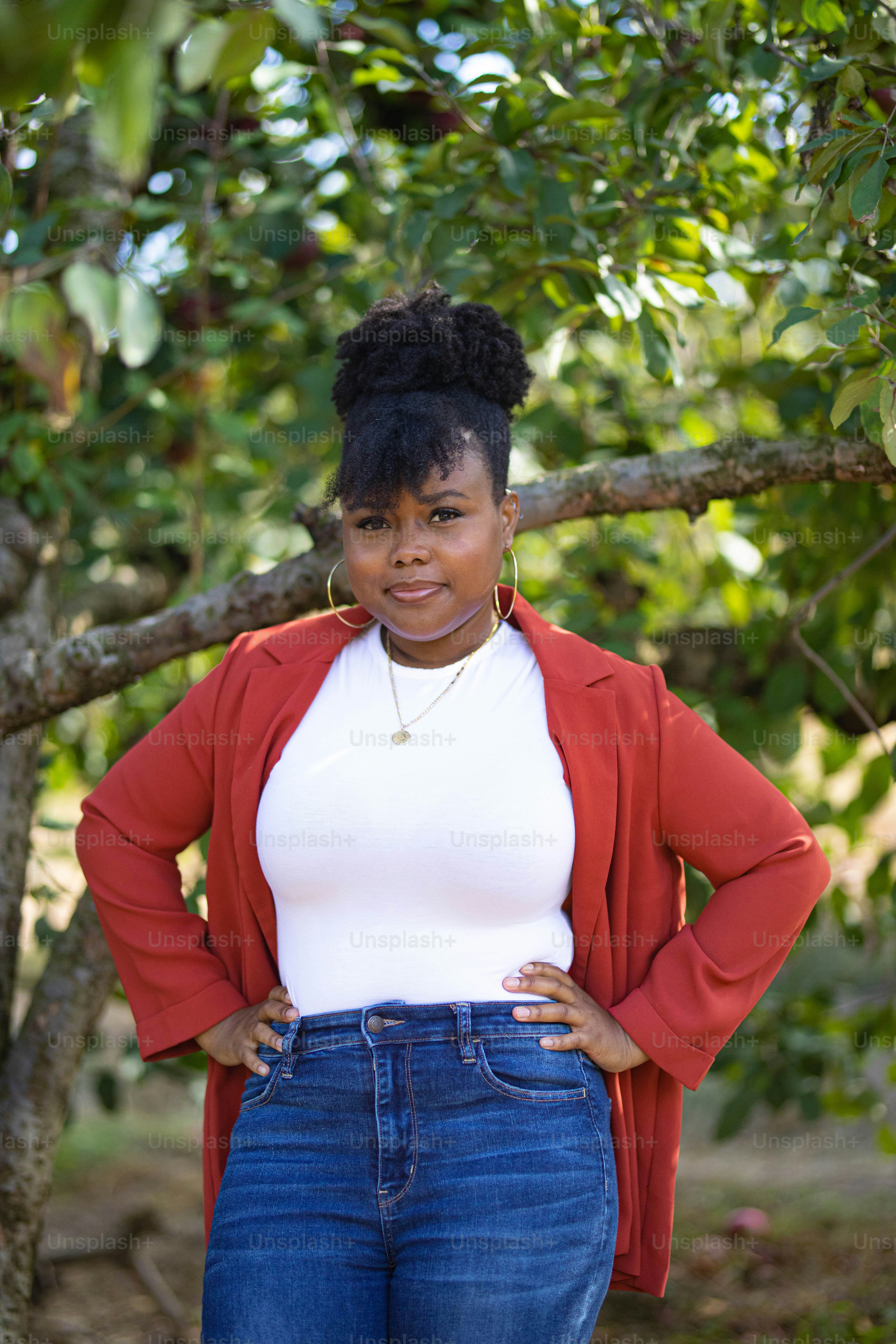 a woman standing in front of a tree with her hands on her hips
