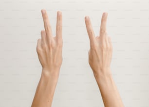 Duas mãos fazendo o sinal de V com os dedos