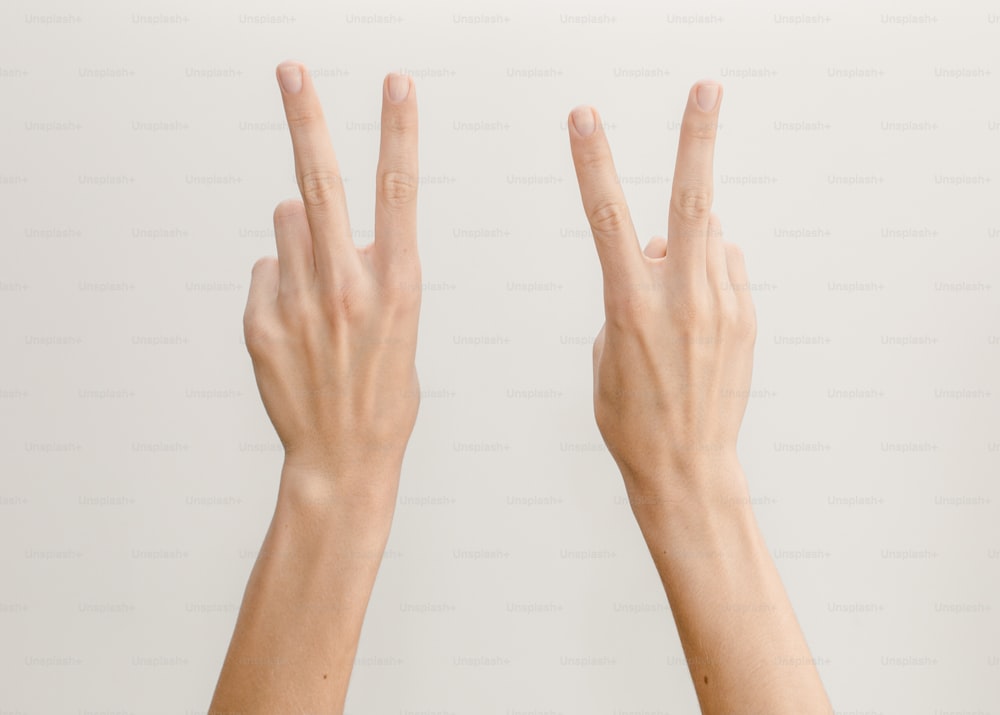 zwei Hände, die mit ihren Fingern das V-Zeichen machen
