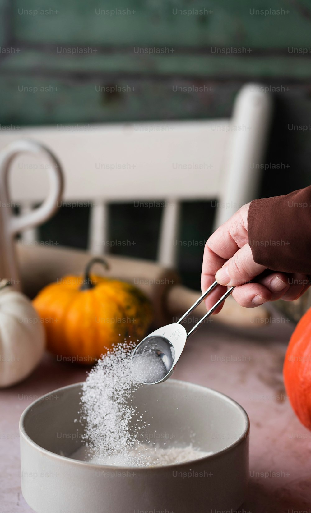 a person scooping sugar into a white bowl