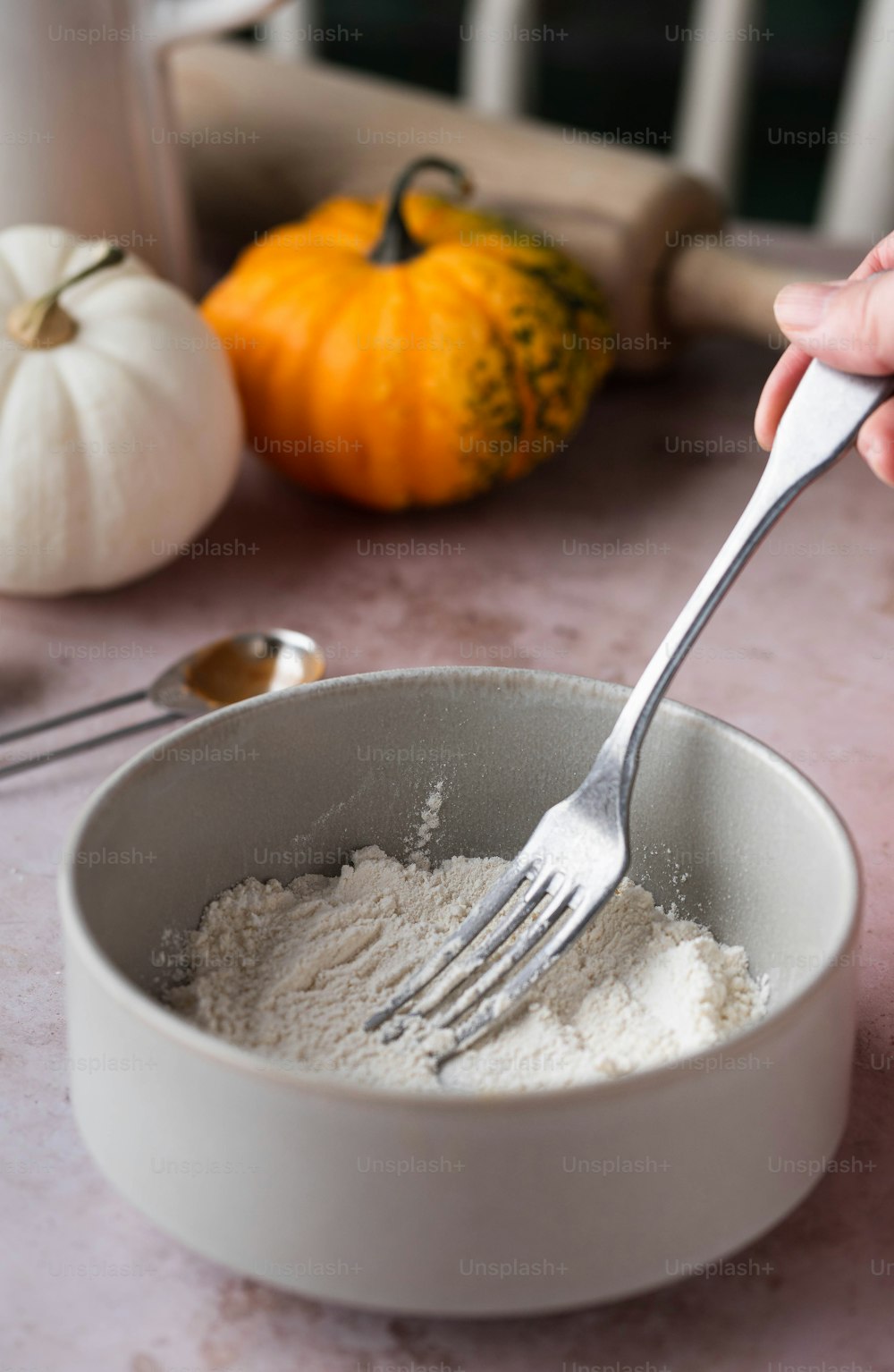 une personne tenant une fourchette dans un bol de farine