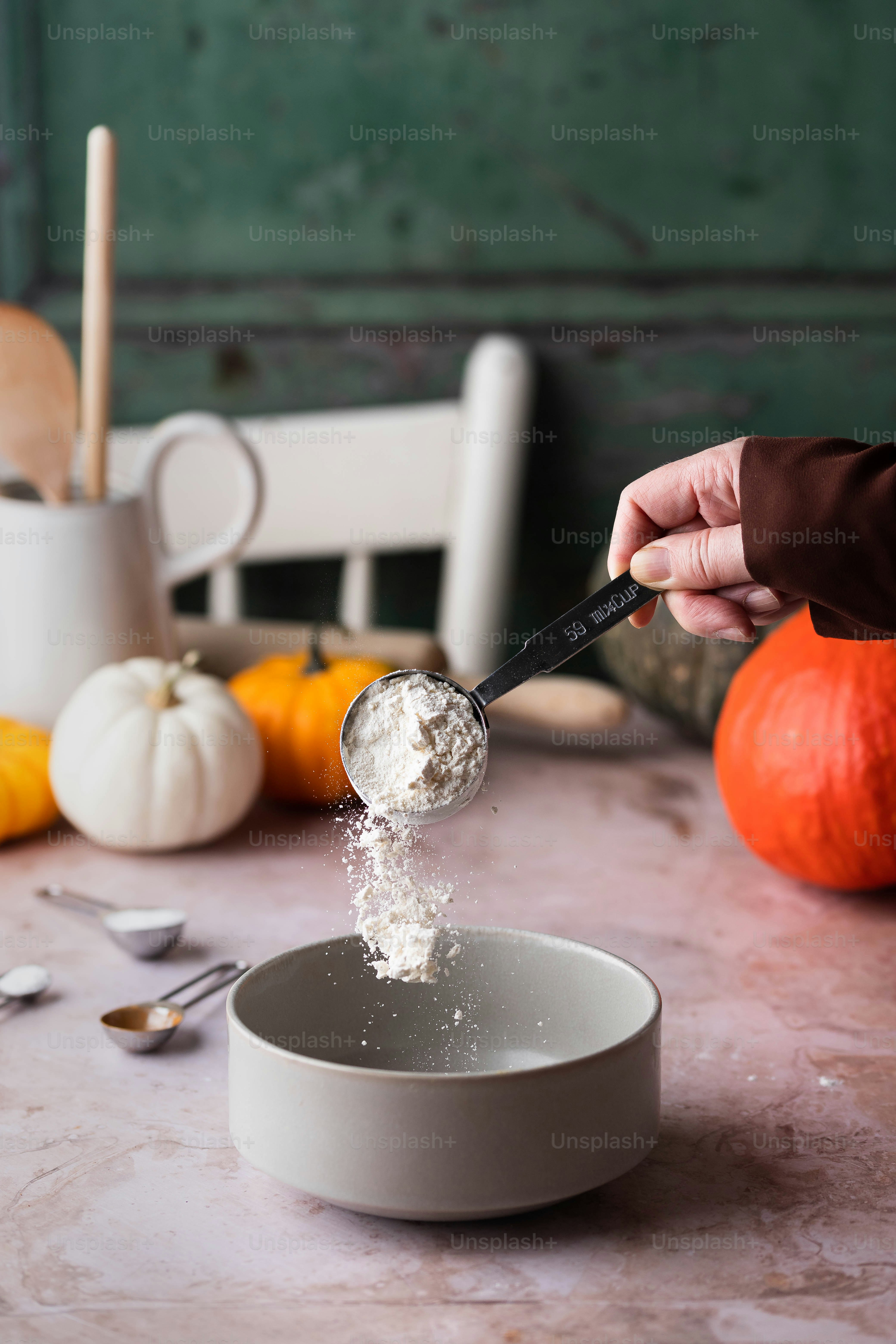 eine Person, die Zucker in eine Schüssel auf einem Tisch schöpft