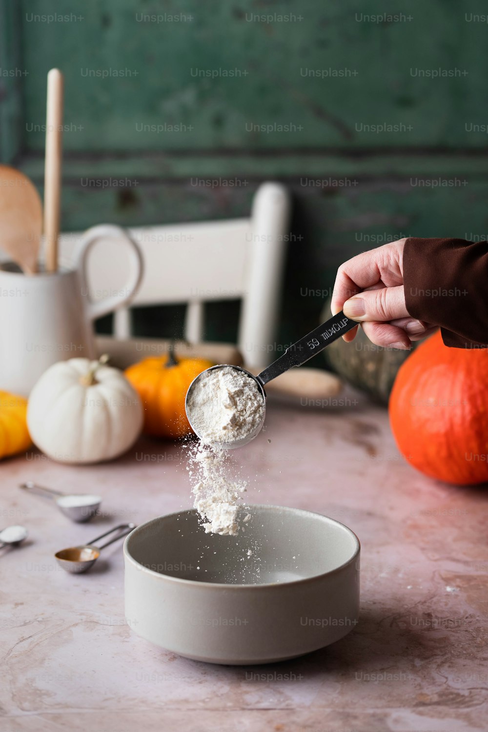 a person scooping sugar into a bowl on a table