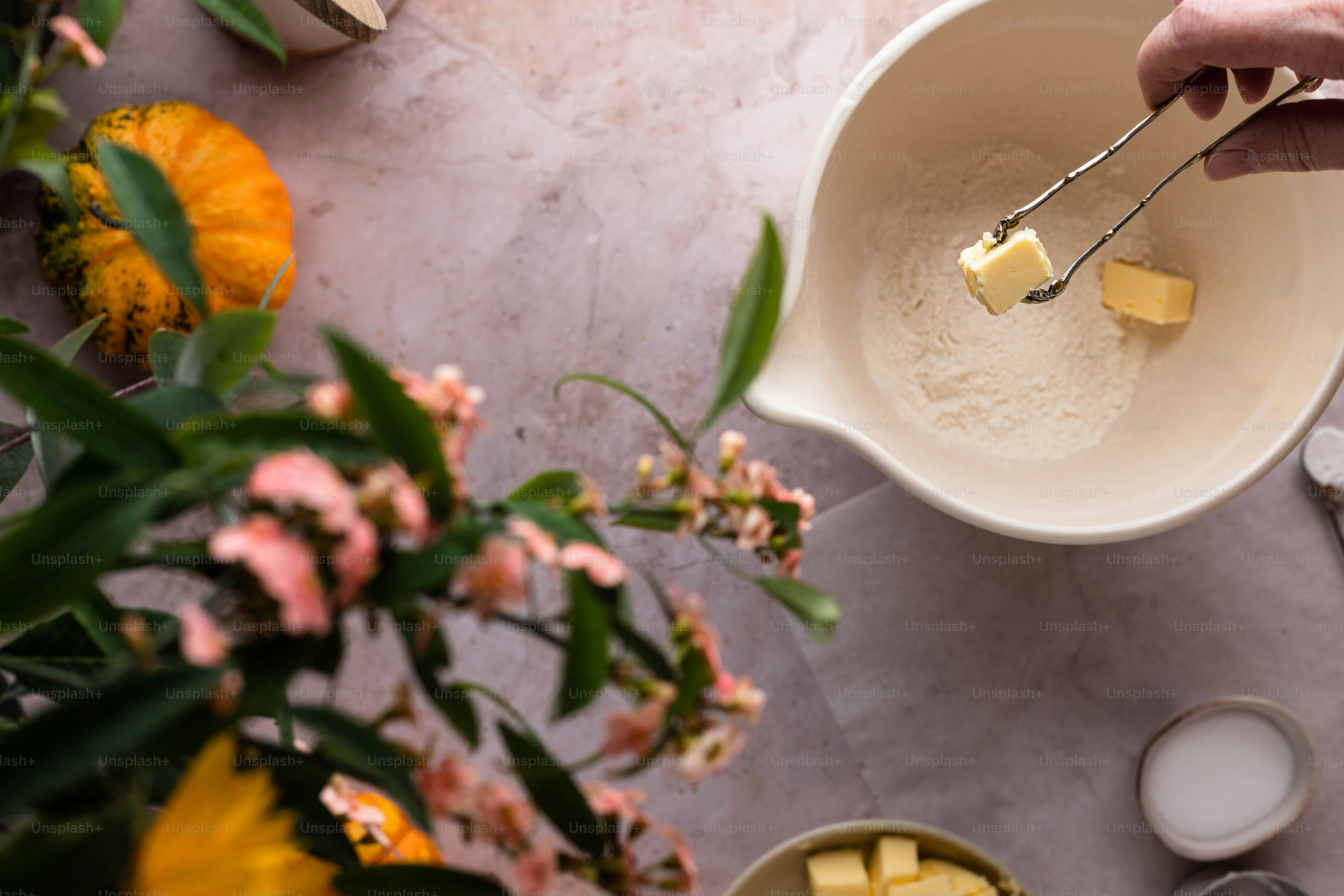 eine Person, die Zucker in eine Schüssel mit Essen schöpft