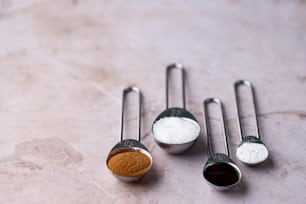 three measuring spoons filled with different types of sugar