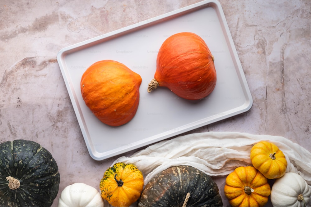 a white tray topped with pumpkins on top of a table