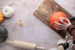 a person carving a pumpkin on a wooden board