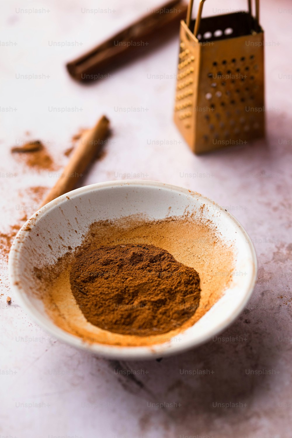 a white bowl filled with brown powder next to a grater