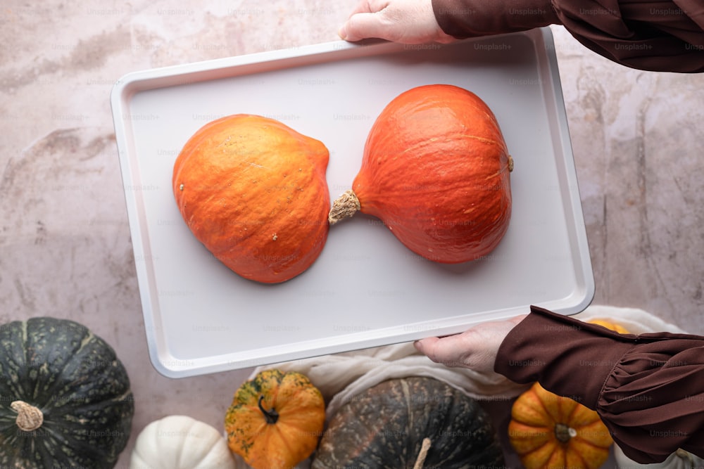 a person holding a tray with pumpkins on it