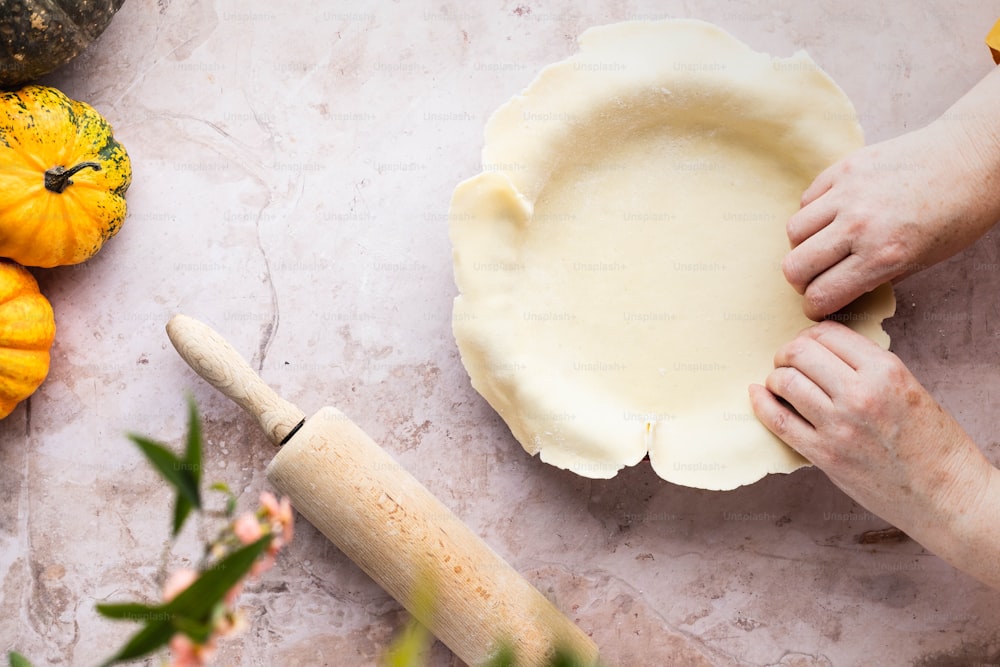 a person rolling out a pie crust on a table