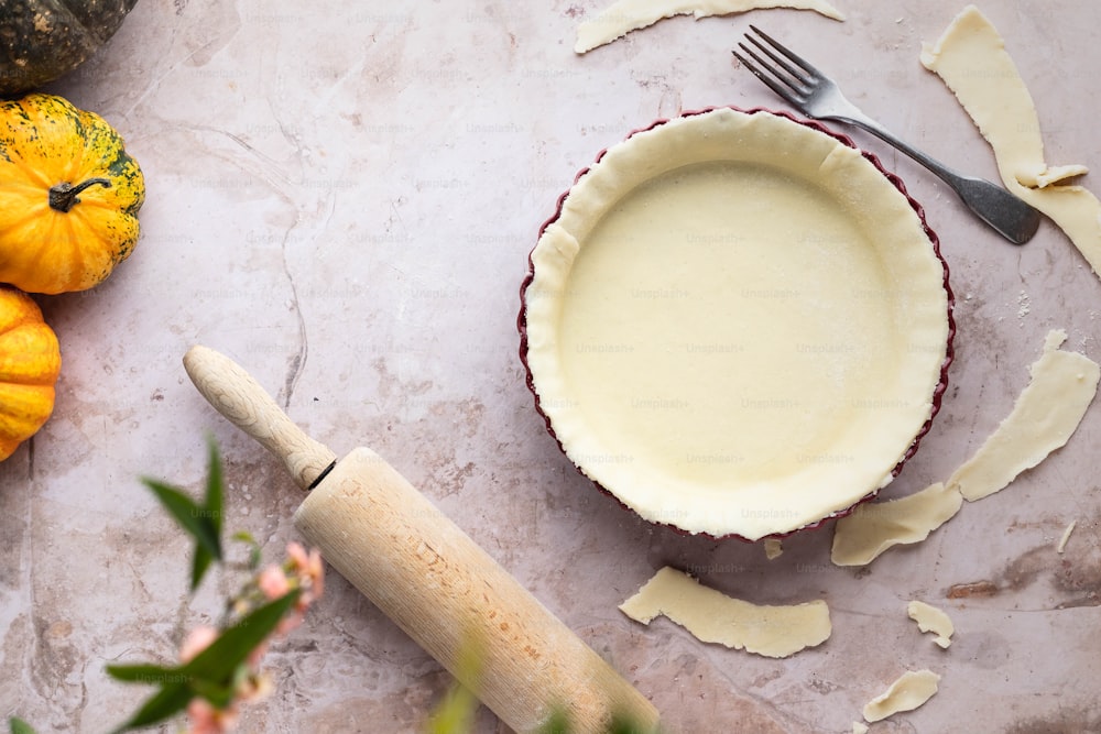 a pie crust in a pie pan next to a rolling pin