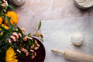 a rolling pin sitting on top of a counter next to flowers
