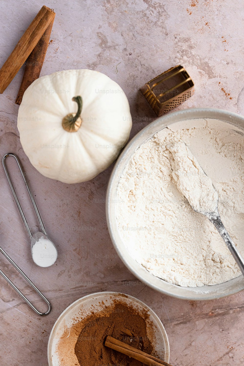 un tavolo con una ciotola di polvere, una zucca, una frusta e