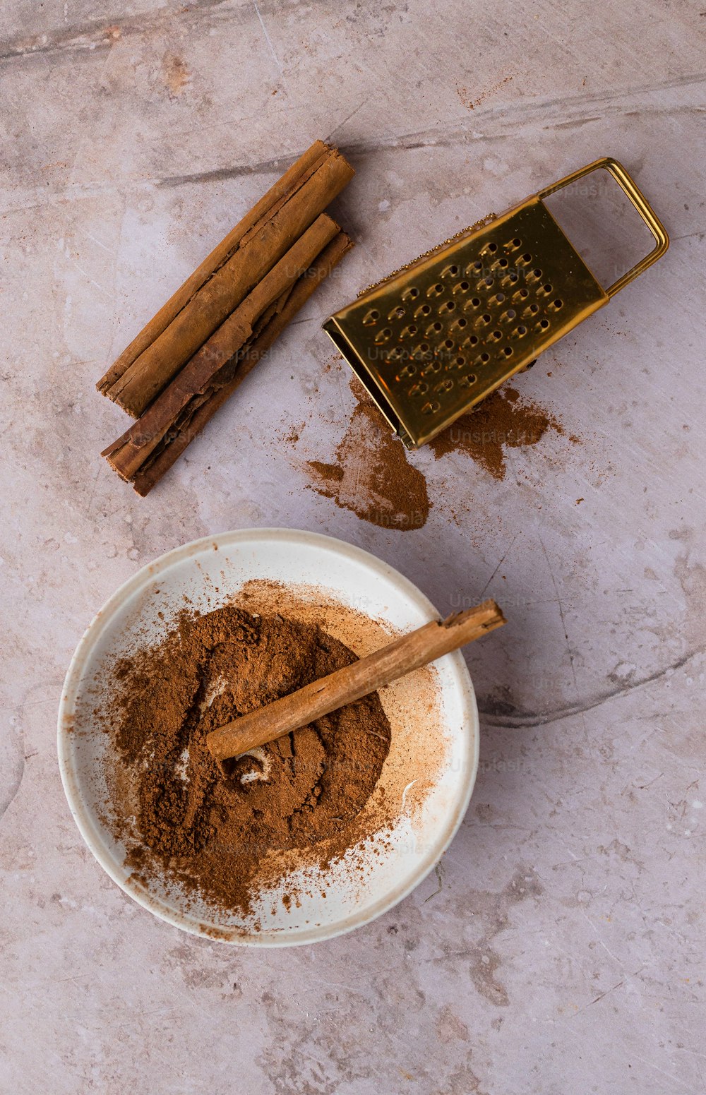 a bowl of cinnamon powder and cinnamon sticks