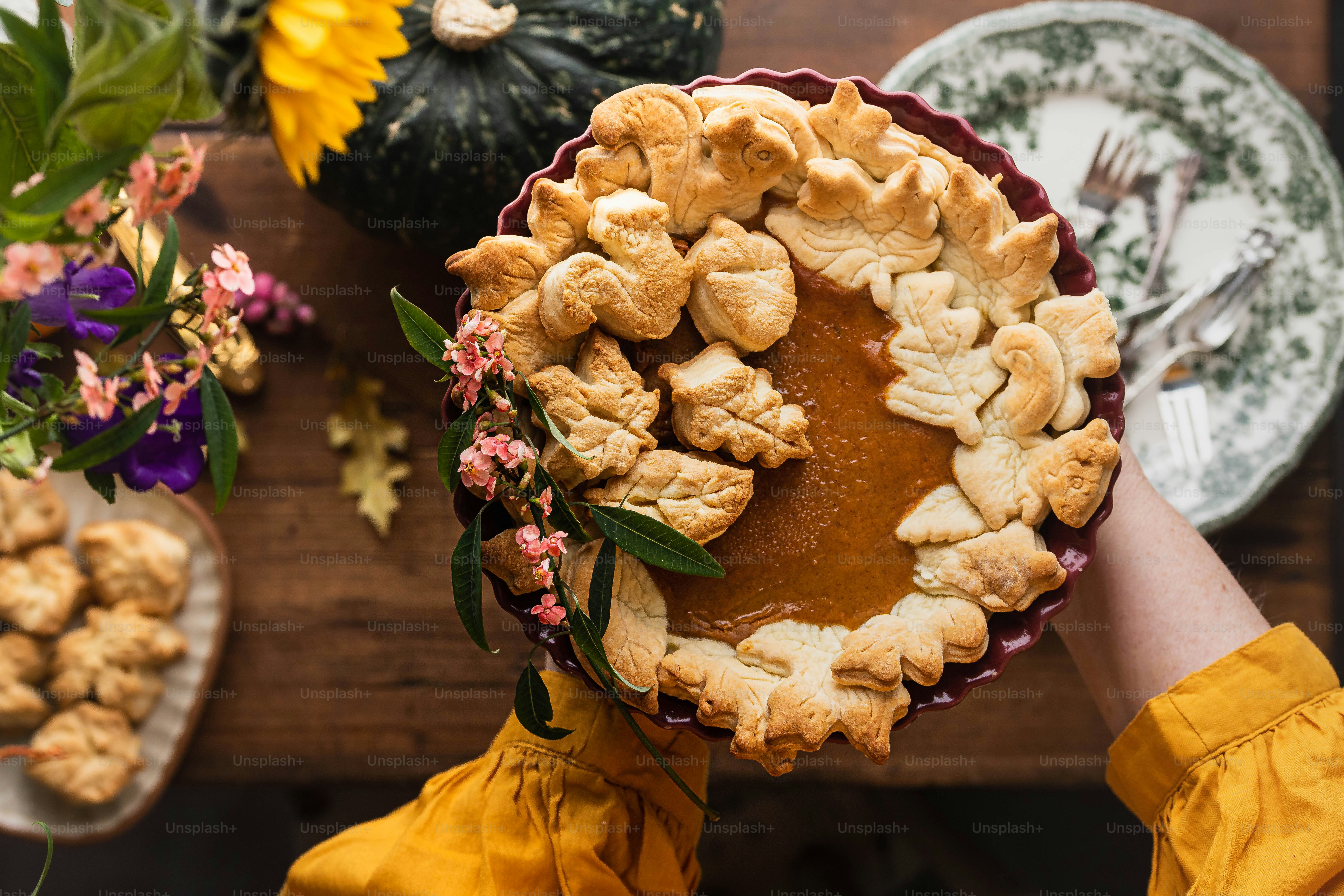 a person holding a pie on top of a wooden table