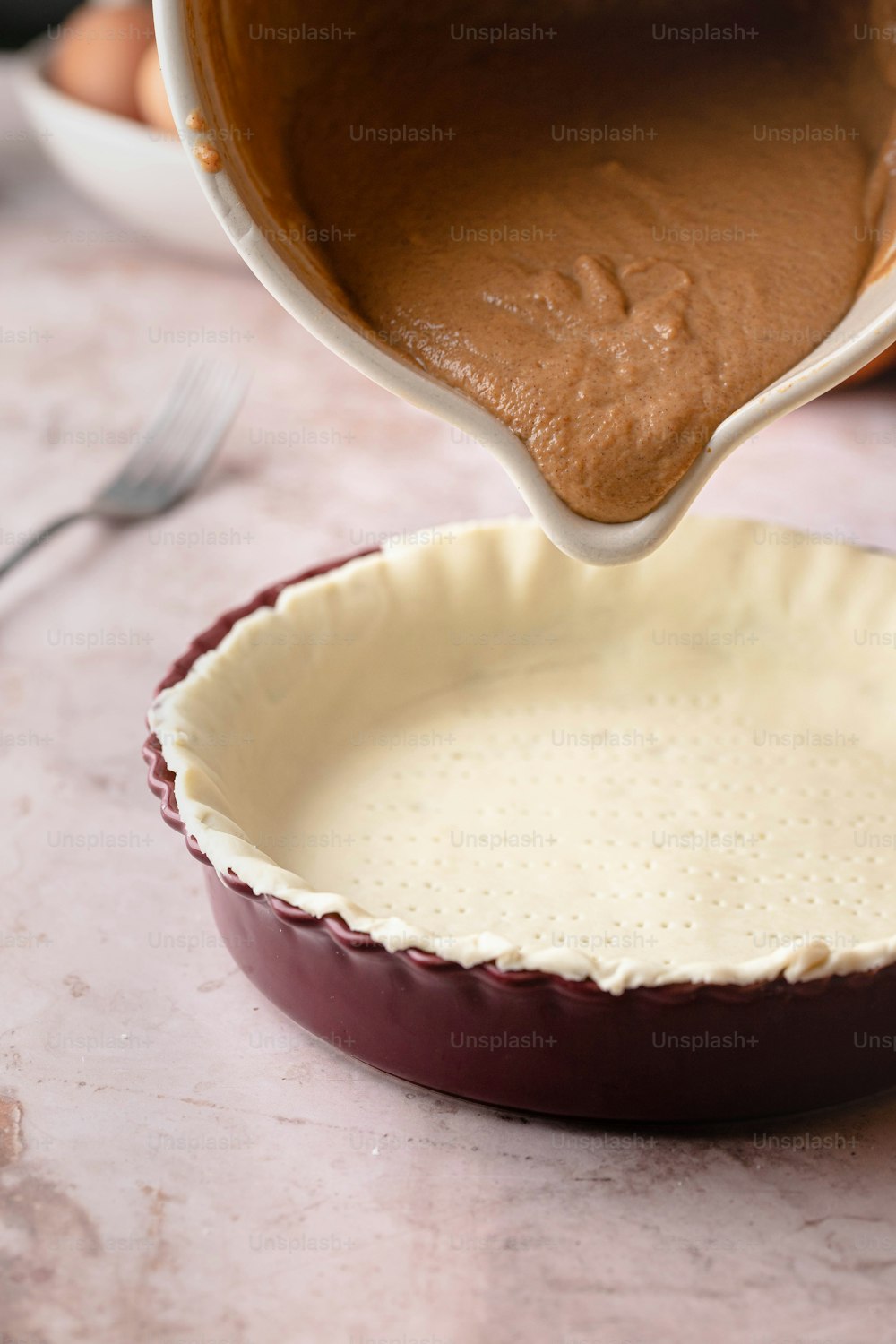 a pie pan filled with chocolate pudding being poured into it