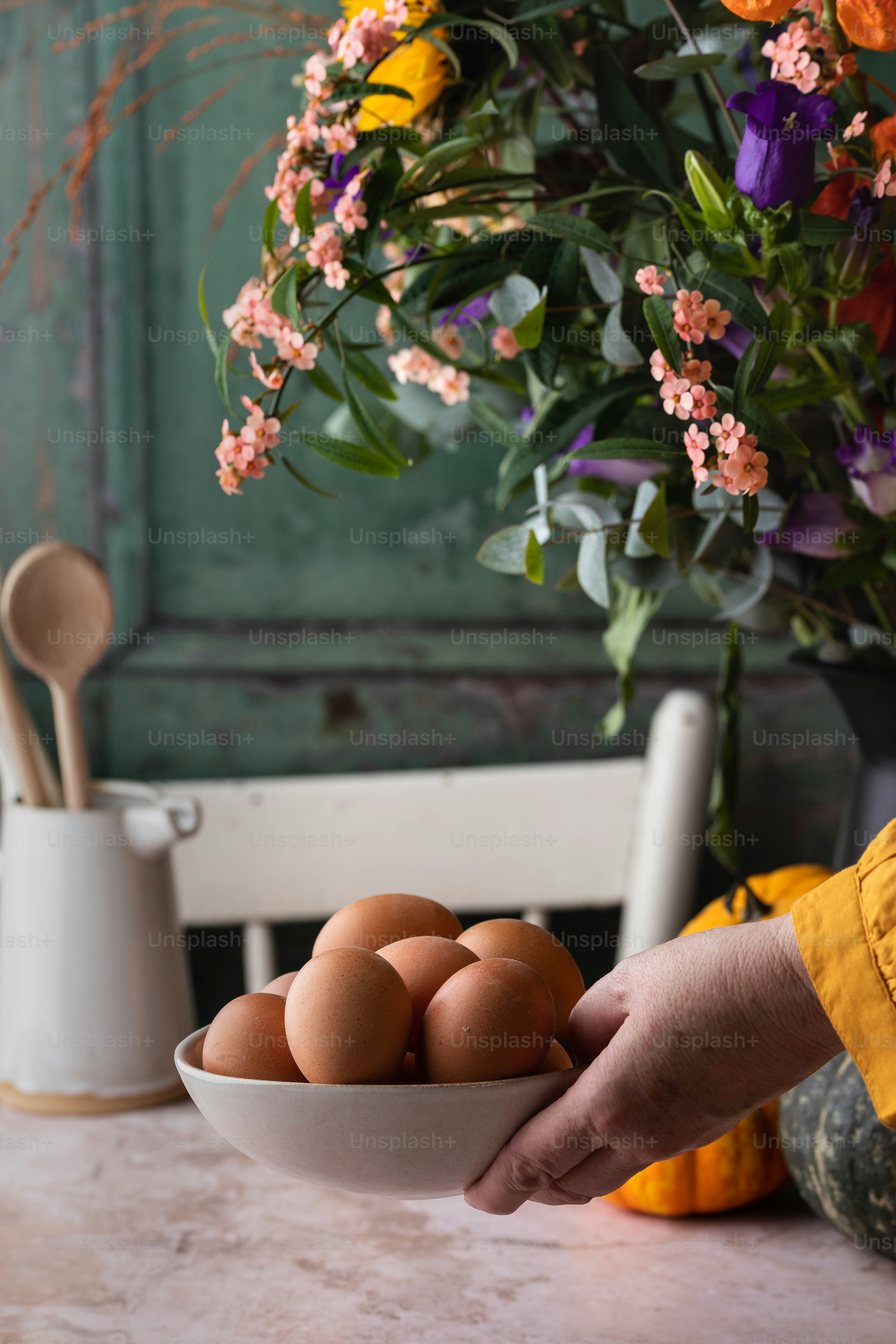 a person holding a bowl of eggs on a table