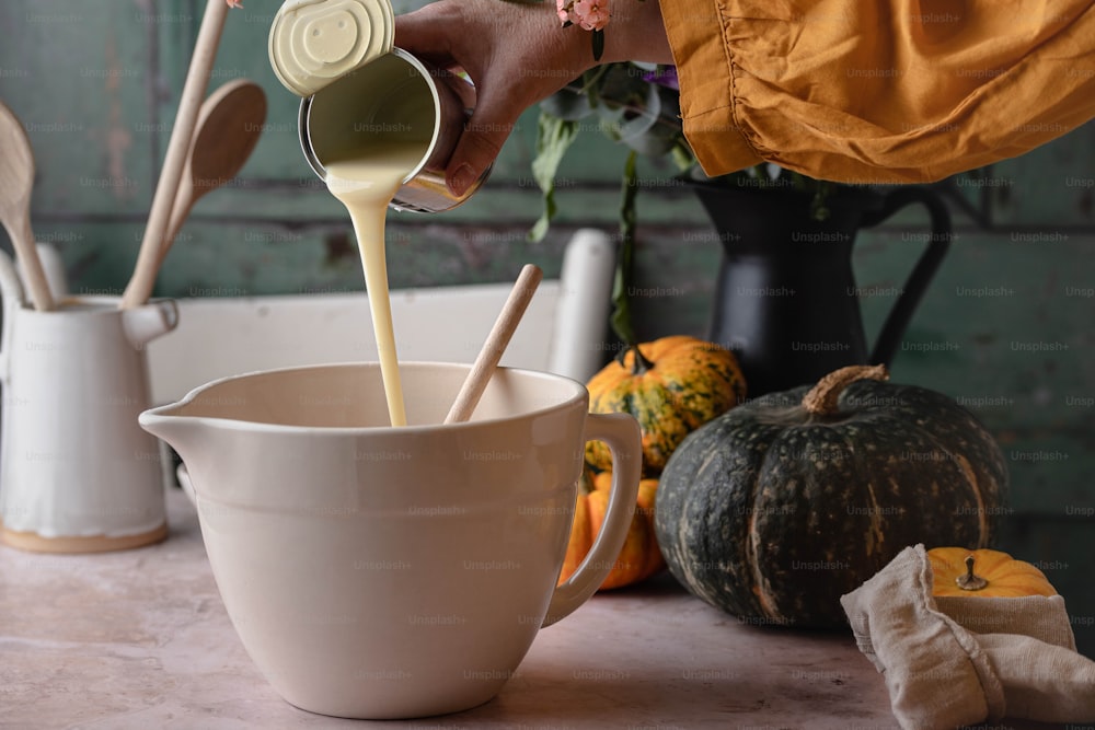 a person pouring milk into a white cup