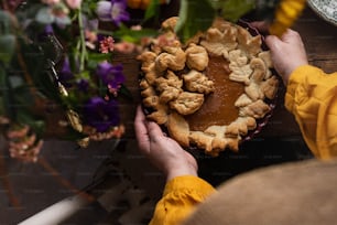 a person holding a pie on top of a wooden table