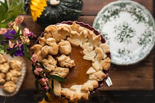 a pie on a table with flowers and plates