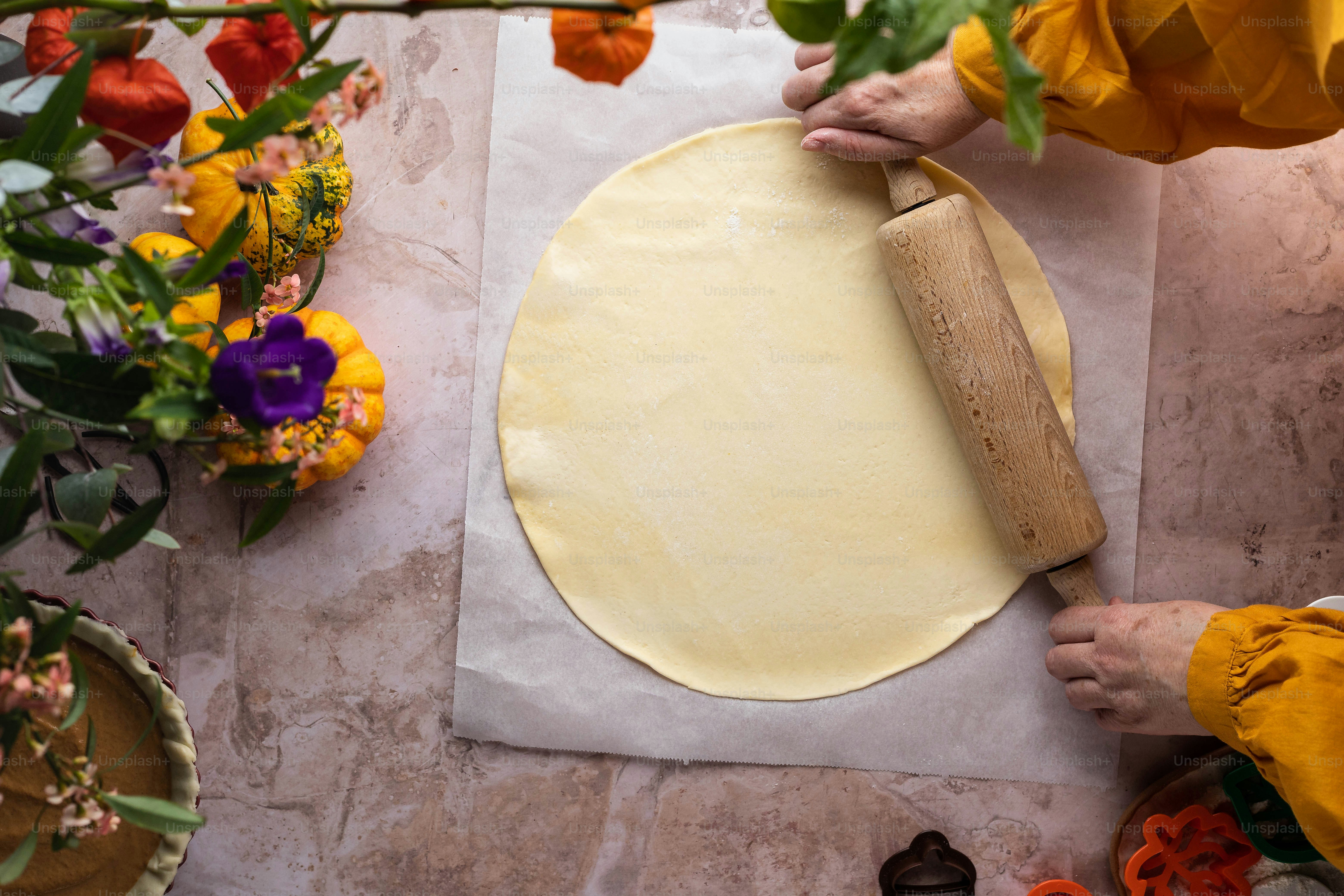 a person rolling dough on a piece of paper