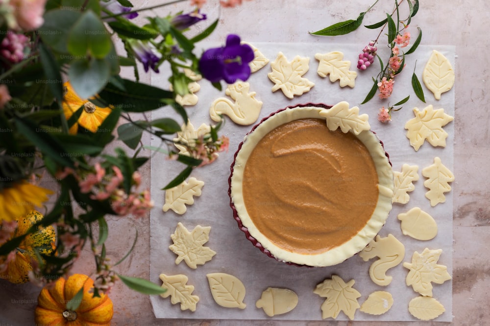 a bowl of peanut butter surrounded by cookies and flowers