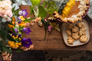 a wooden table topped with a pie and flowers