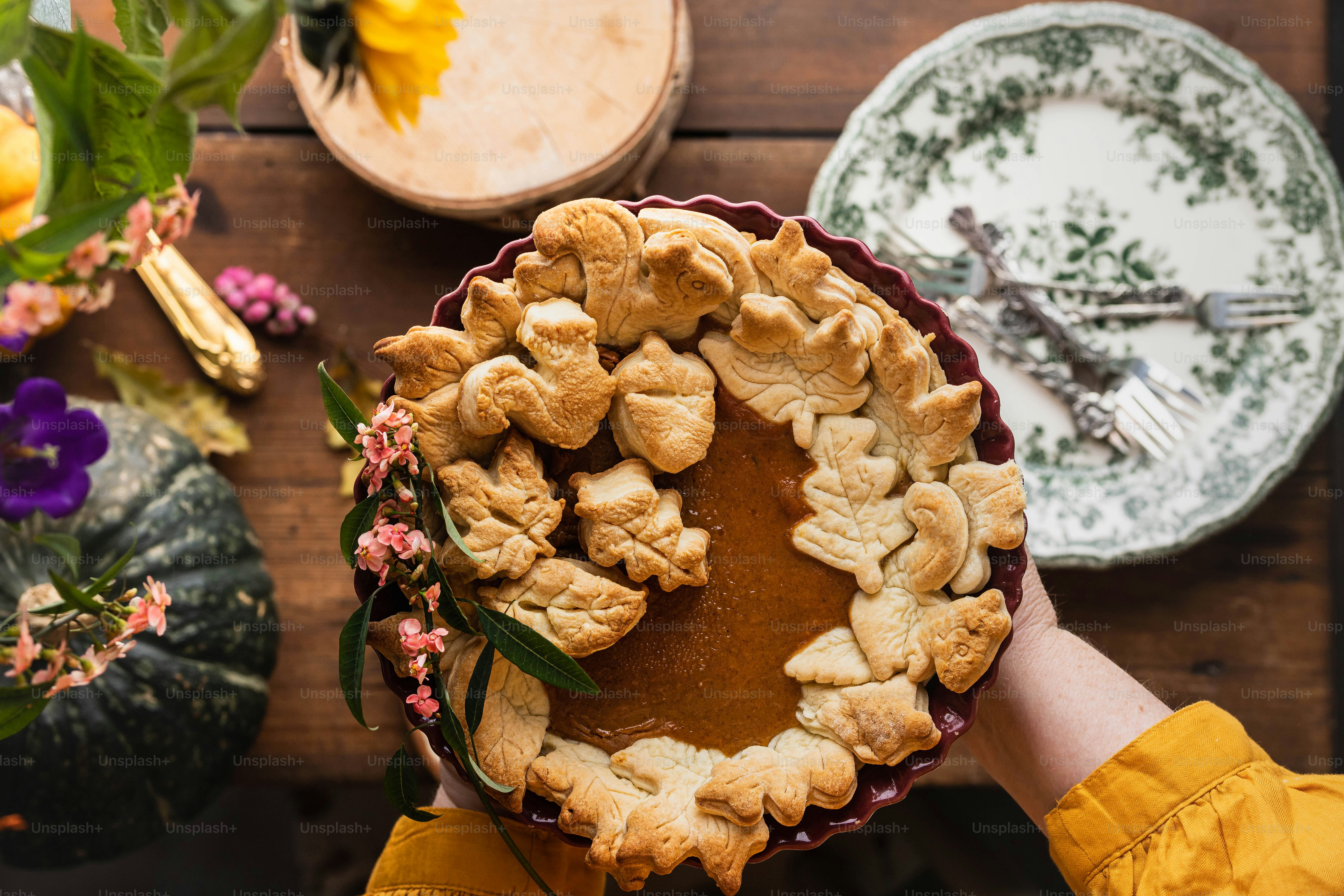 a person holding a pie on top of a wooden table