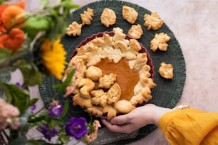 a person holding a pie on top of a green plate
