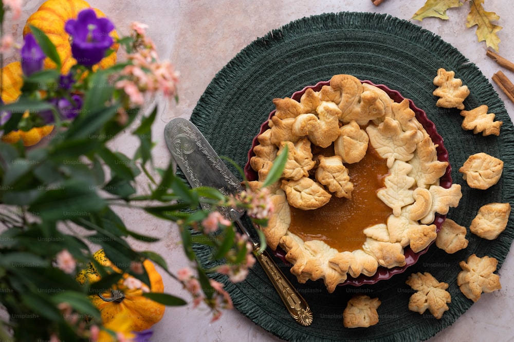 a pie on a green plate with a knife and flowers