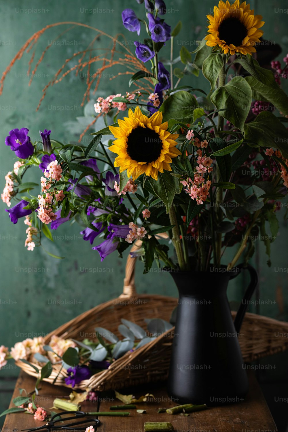 eine schwarze Vase gefüllt mit vielen lila und gelben Blumen