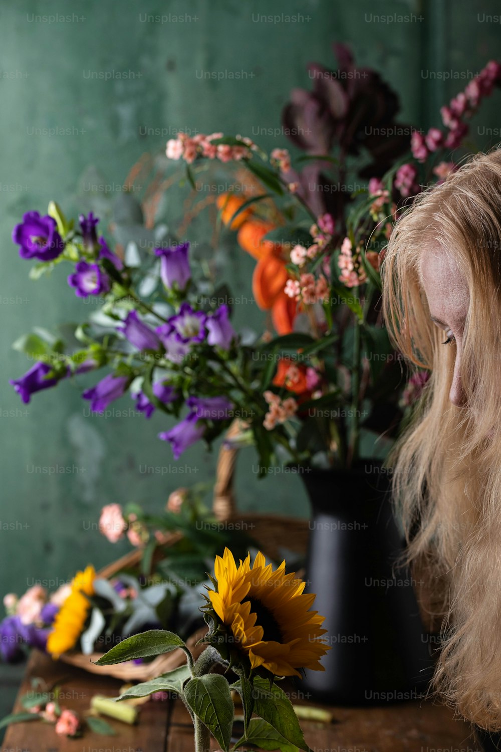 a woman looking at a vase of flowers