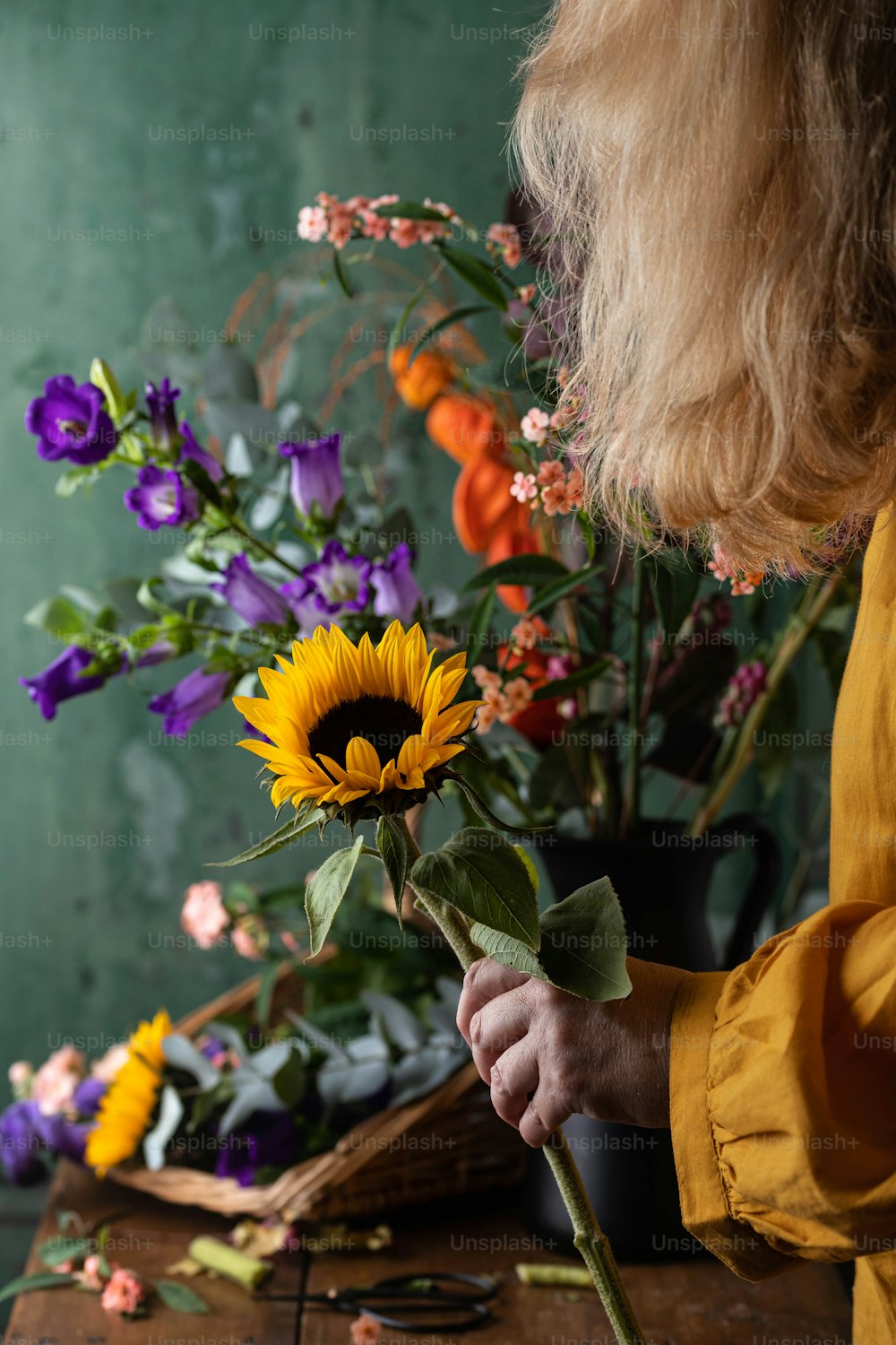 a woman arranging flowers in a vase on a table