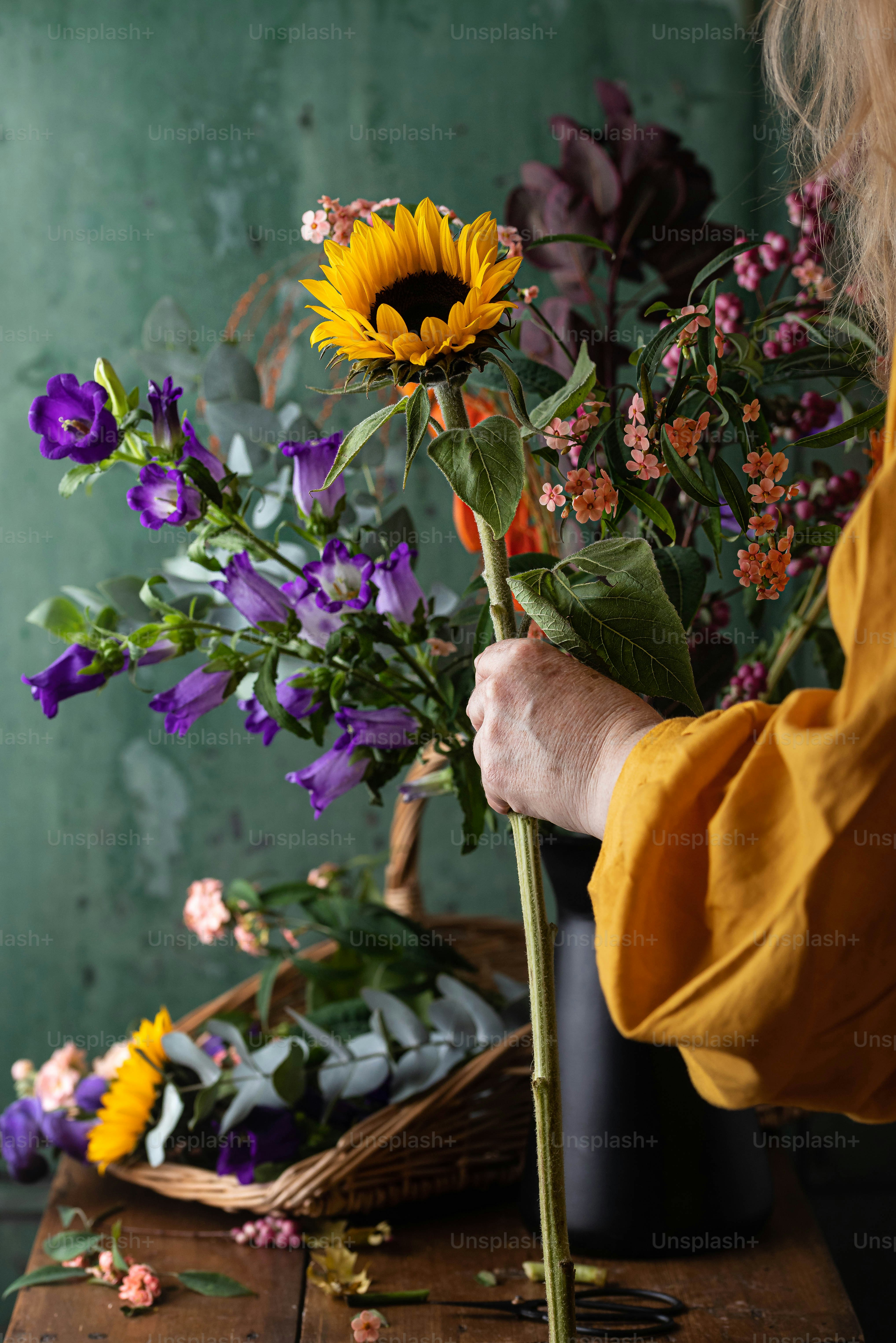 a woman arranging flowers in a vase on a table