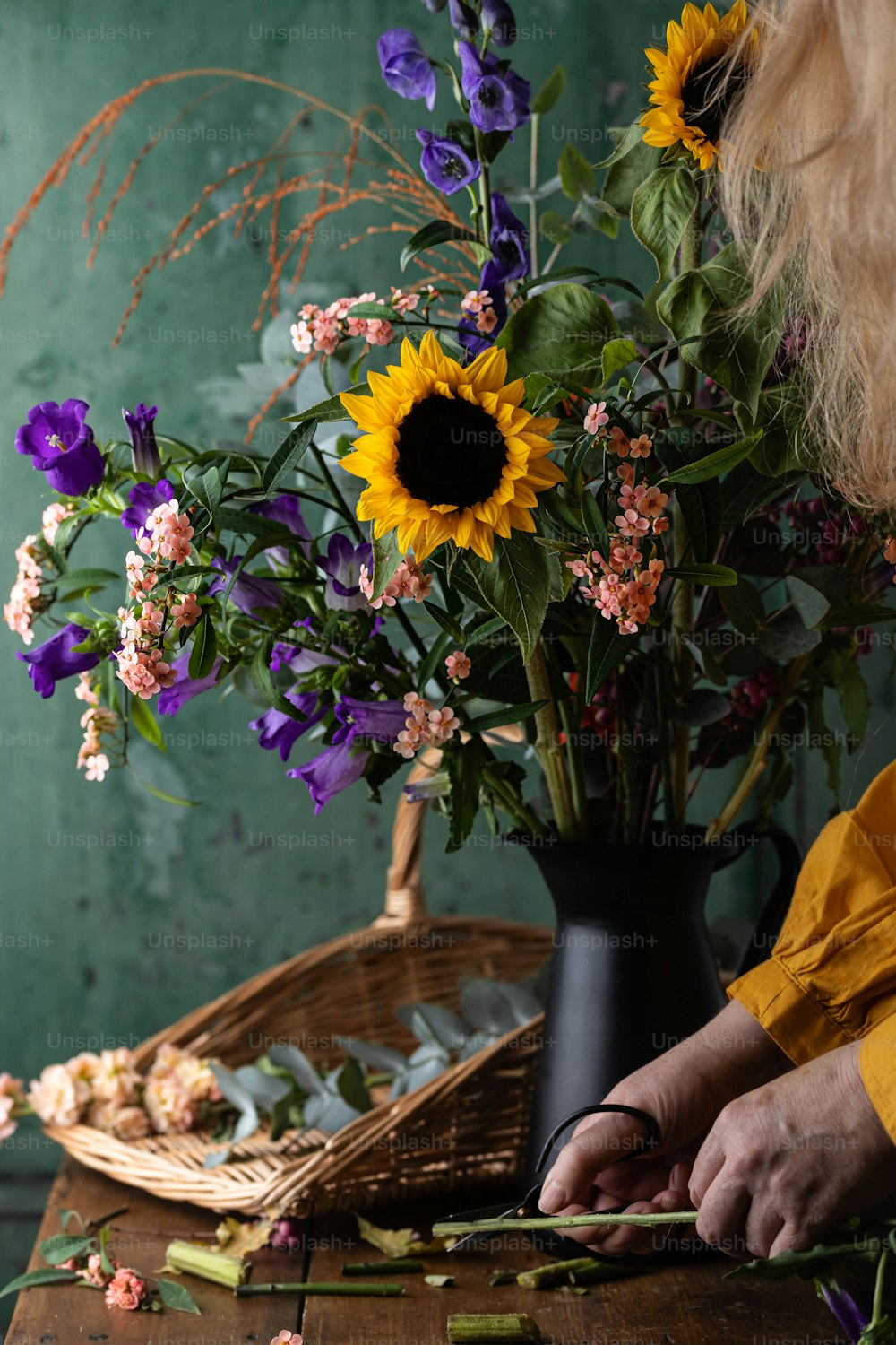 uma mulher arranjando flores em um vaso em uma mesa