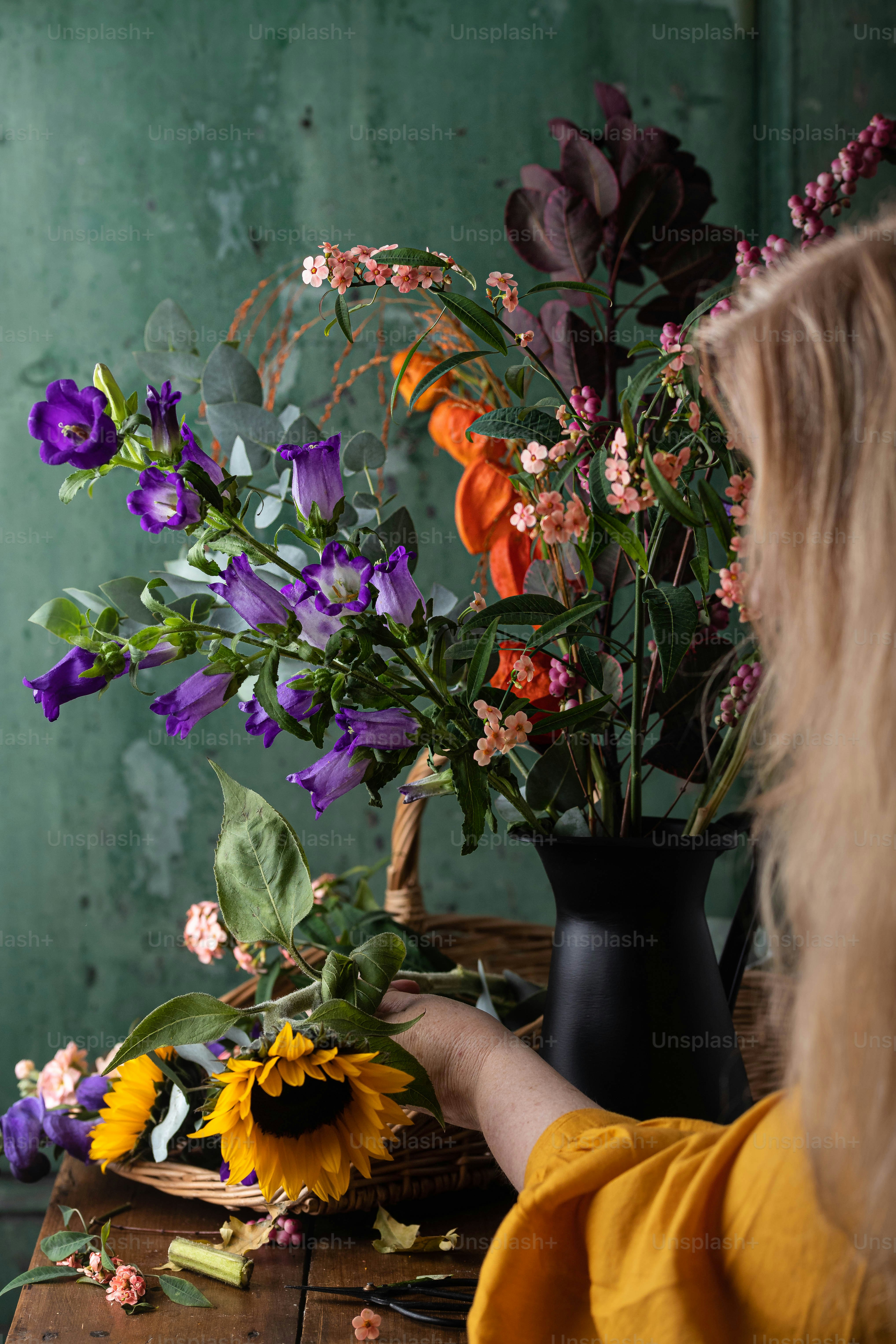 Una mujer arreglando flores en un jarrón sobre una mesa