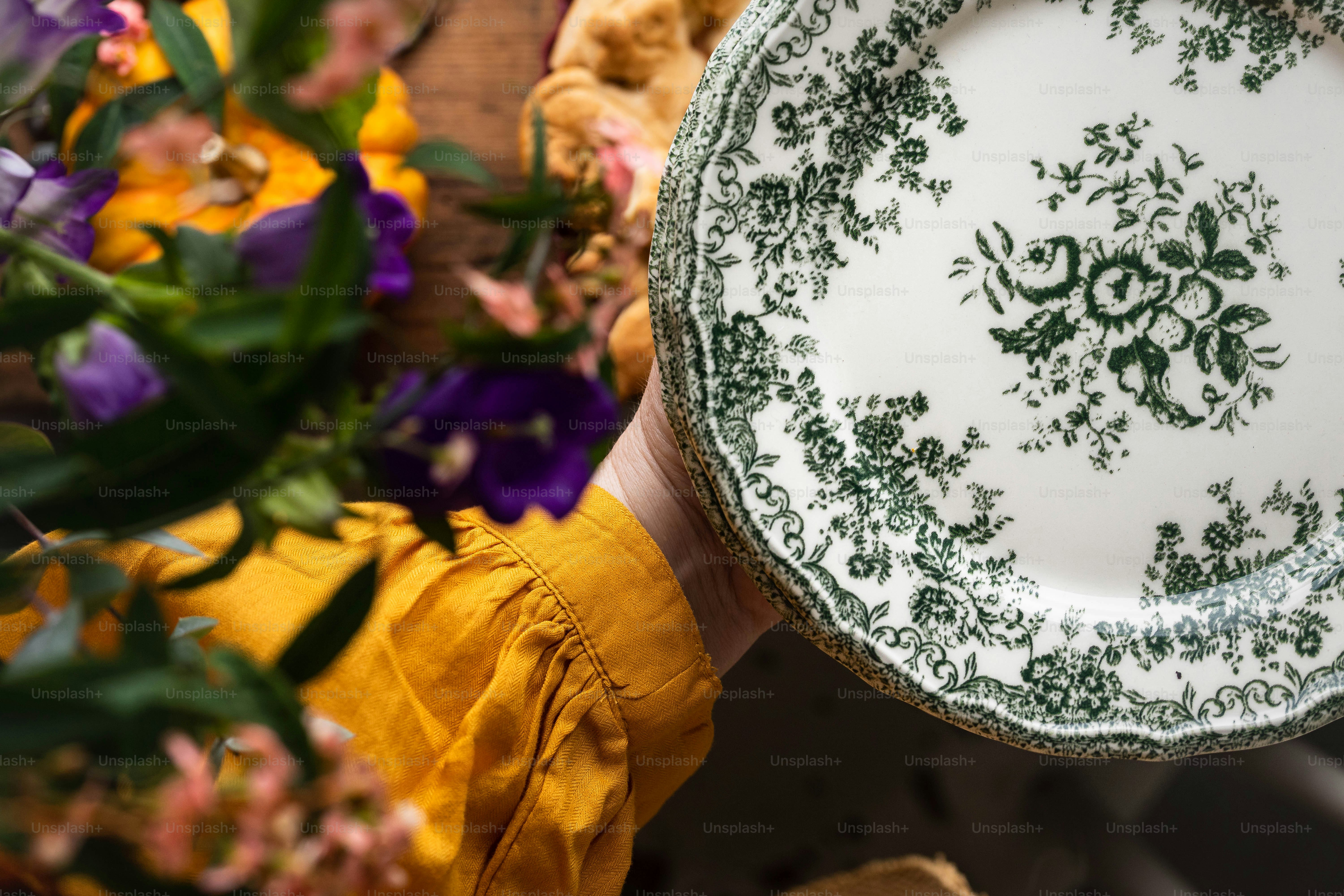 eine Person, die einen Teller mit Blumen im Hintergrund hält