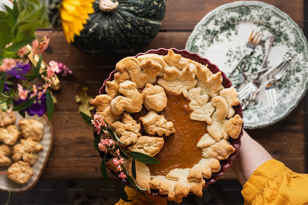 a person holding a pie on top of a wooden table