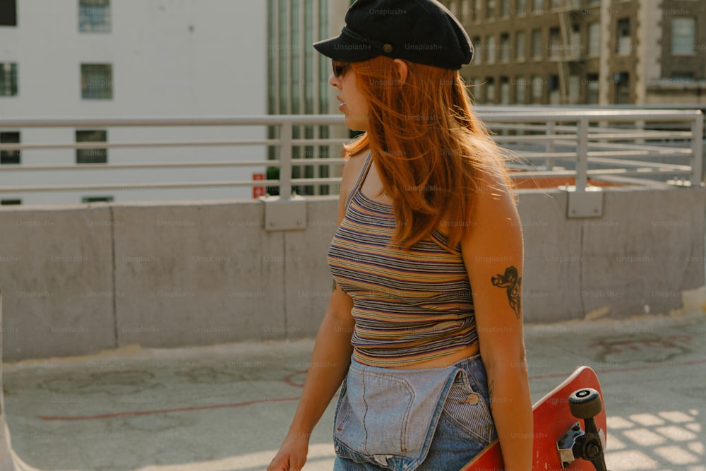 Eine junge Frau, die ein Skateboard eine Straße entlang trägt