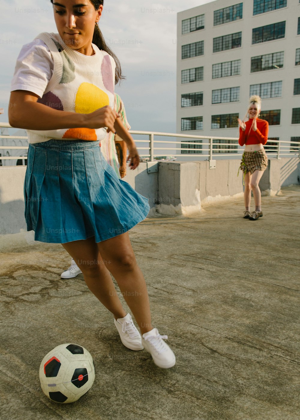 uma mulher de saia azul chutando uma bola de futebol