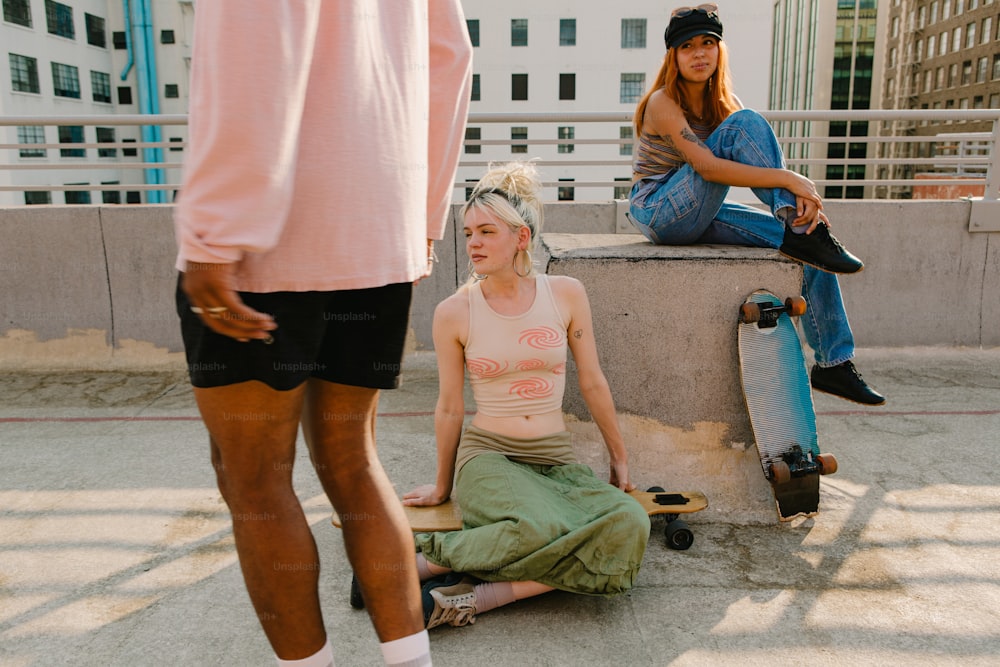 Una donna seduta a terra accanto a uno skateboard